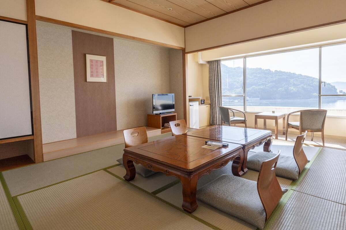 Een traditionele Japanse kamer met tatami vloerbedekking, een houten tafel en stoelen.