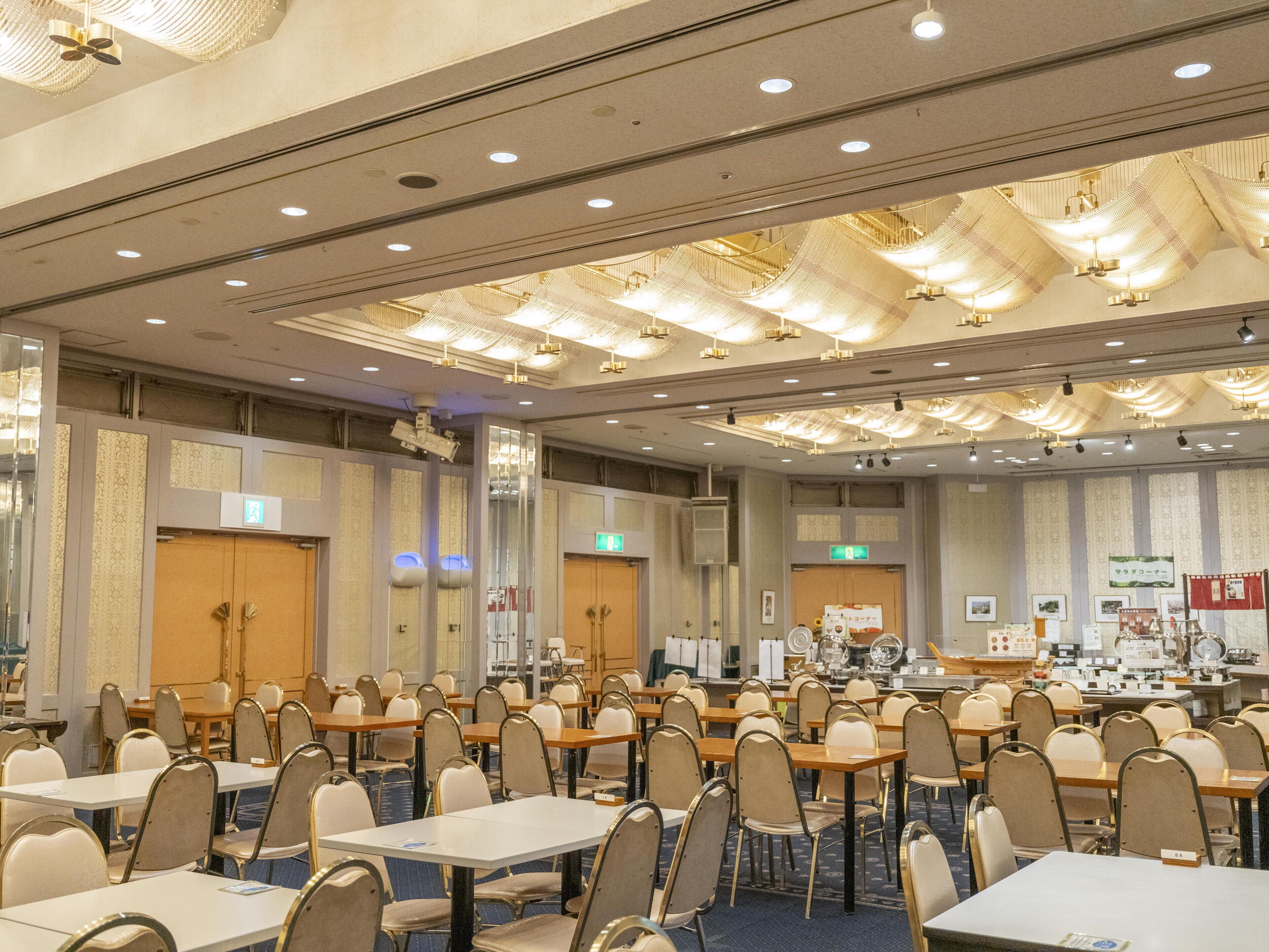 A conference room with rows of tables and chairs, equipped with nameplates, a projector, and a presentation screen.