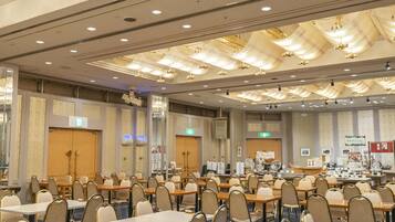A conference room with rows of tables and chairs, equipped with nameplates, a projector, and a presentation screen.