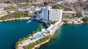 Oversigtsbillede af et kysthotel med swimmingpool, flere bygninger og en mole.