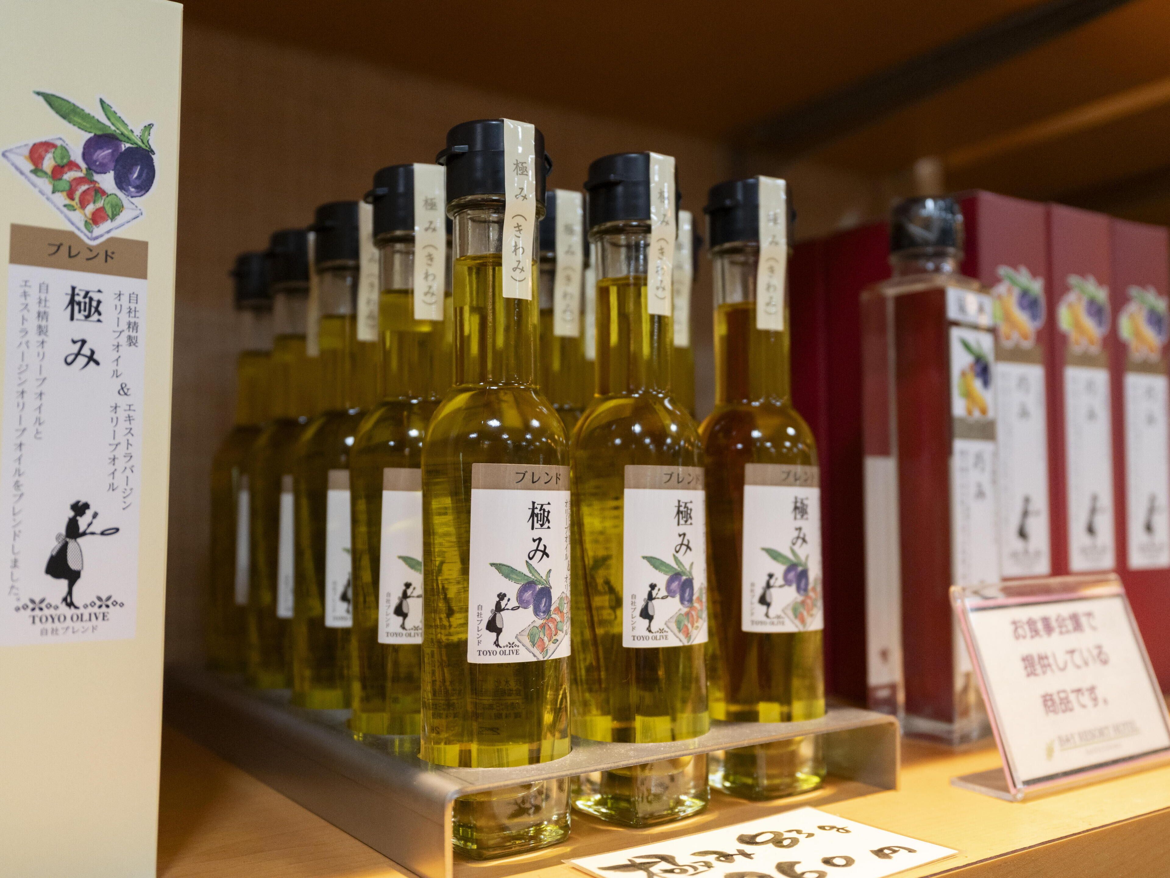 A display of olive oil bottles with labels, arranged on a shelf.
