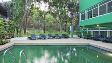 Una piscina al aire libre, sombrillas, tumbonas