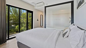 A modern bedroom with a large bed, a sliding glass door to a balcony, and a large mirror. - The Kingsford, an Ascend Collection Hotel (Hamilton)