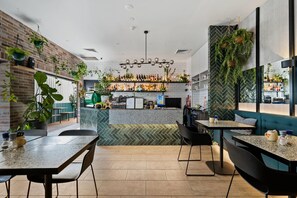 A modern restaurant interior with brick walls, hanging plants, a herringbone-patterned backsplash, and a bar area. - The Kingsford, an Ascend Collection Hotel (Hamilton)