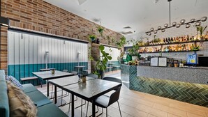 A restaurant with brick walls, green and white decor, and a bar area with shelves of bottles. - The Kingsford, an Ascend Collection Hotel (Hamilton)
