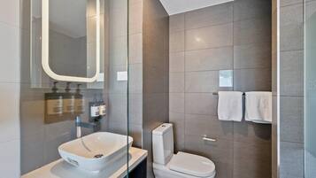 A modern bathroom with a large mirror, a white sink, and a toilet.