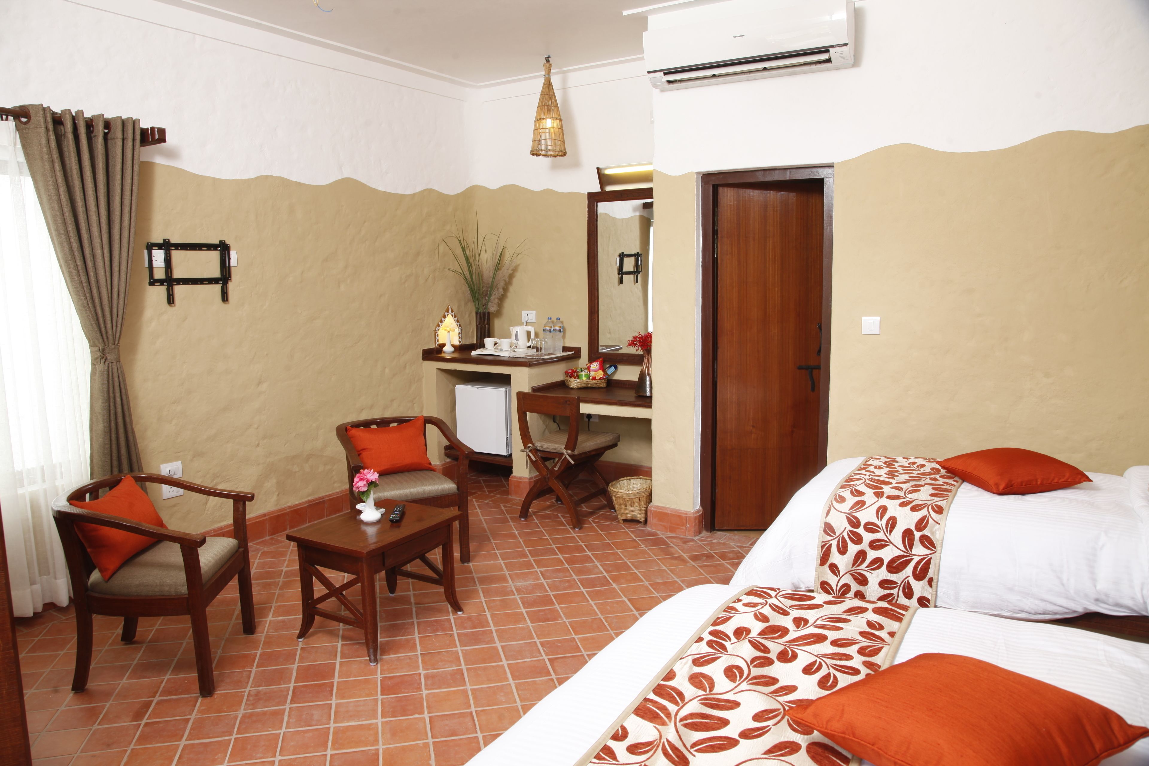 A hotel room with a bed, two chairs, a desk, a small table, and a mirror.