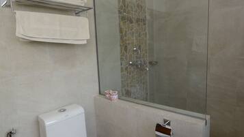 Un baño moderno con ducha envuelta en vidrio, inodoro y perchero.