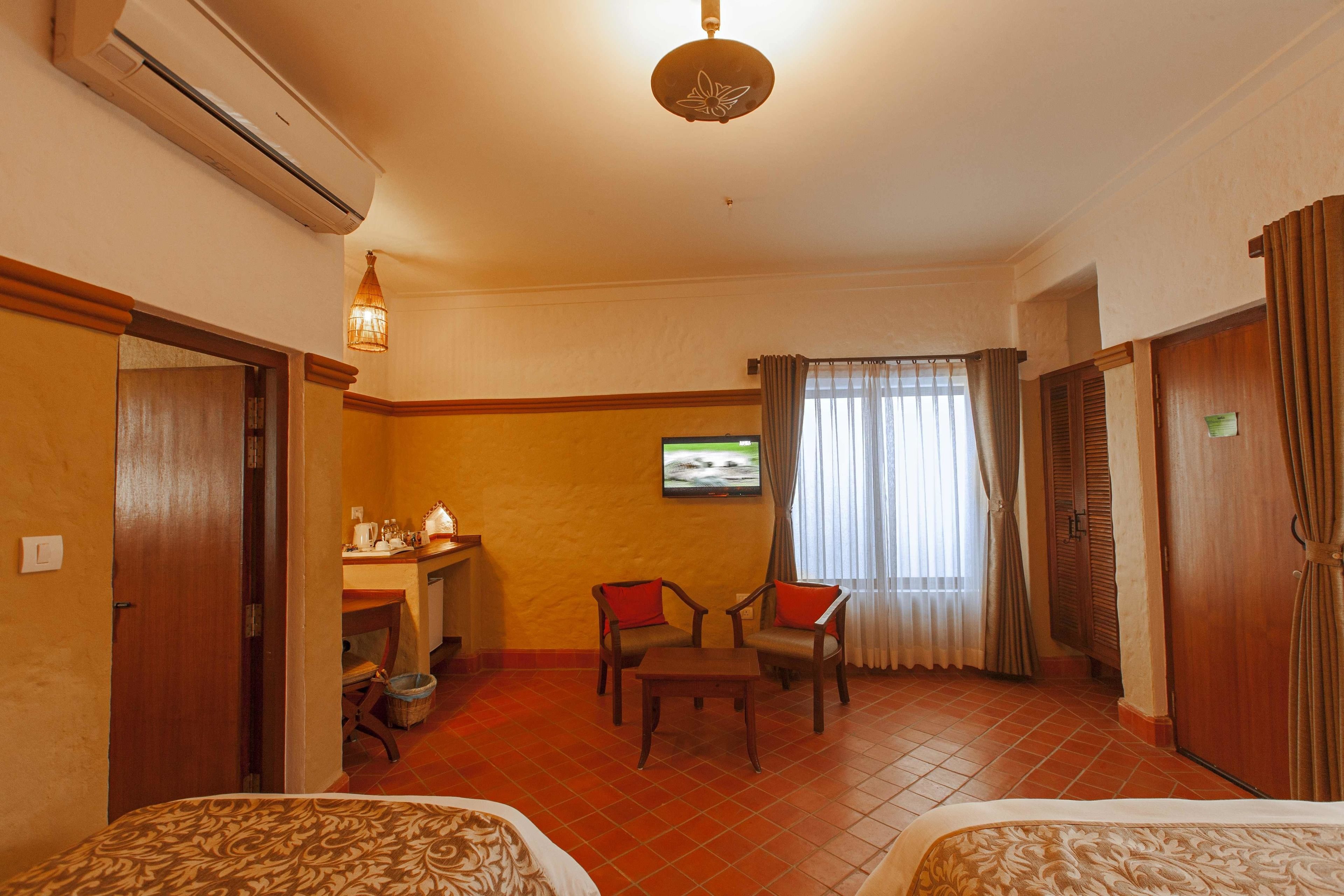 A hotel room with two beds, a desk with a chair, a television, and a window with curtains.