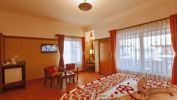 A hotel room with a bed, a desk, a chair, a television, and a view of the outdoors.