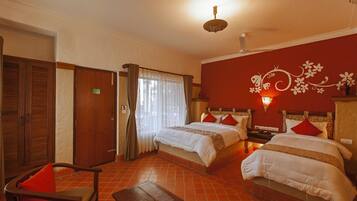 Ein Hotelzimmer mit zwei Betten, einem Holzhocker, einem kleinen Tisch und einer Wandverzierung.