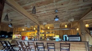 A rustic wooden bar area with several chairs and a counter. - Green Park Chitwan (Sauraha)