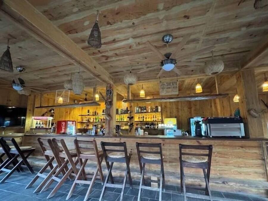 Un coin bar rustique en bois, avec plusieurs chaises et un comptoir.