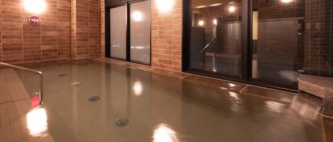A modern indoor pool area with a glass barrier, tiled walls, and a visible water feature.