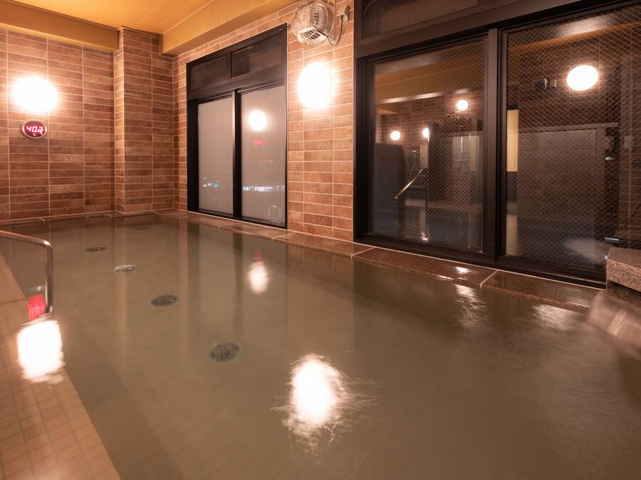 A modern indoor pool area with a glass barrier, tiled walls, and a visible water feature.