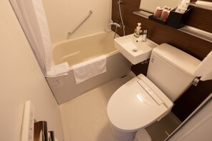 A small, clean bathroom with a white bathtub, a toilet, and a sink.