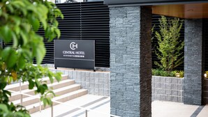 A sign for the Central Hotel with a modern architectural design, featuring stone and metal elements, and a staircase leading to the entrance. - Central Hotel Takeo Onsen (Takeo)