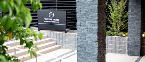 Schild des Central Hotels, architektonisch modern gestaltet, mit Stein- und Metallelementen, und einer Treppe zum Eingang.