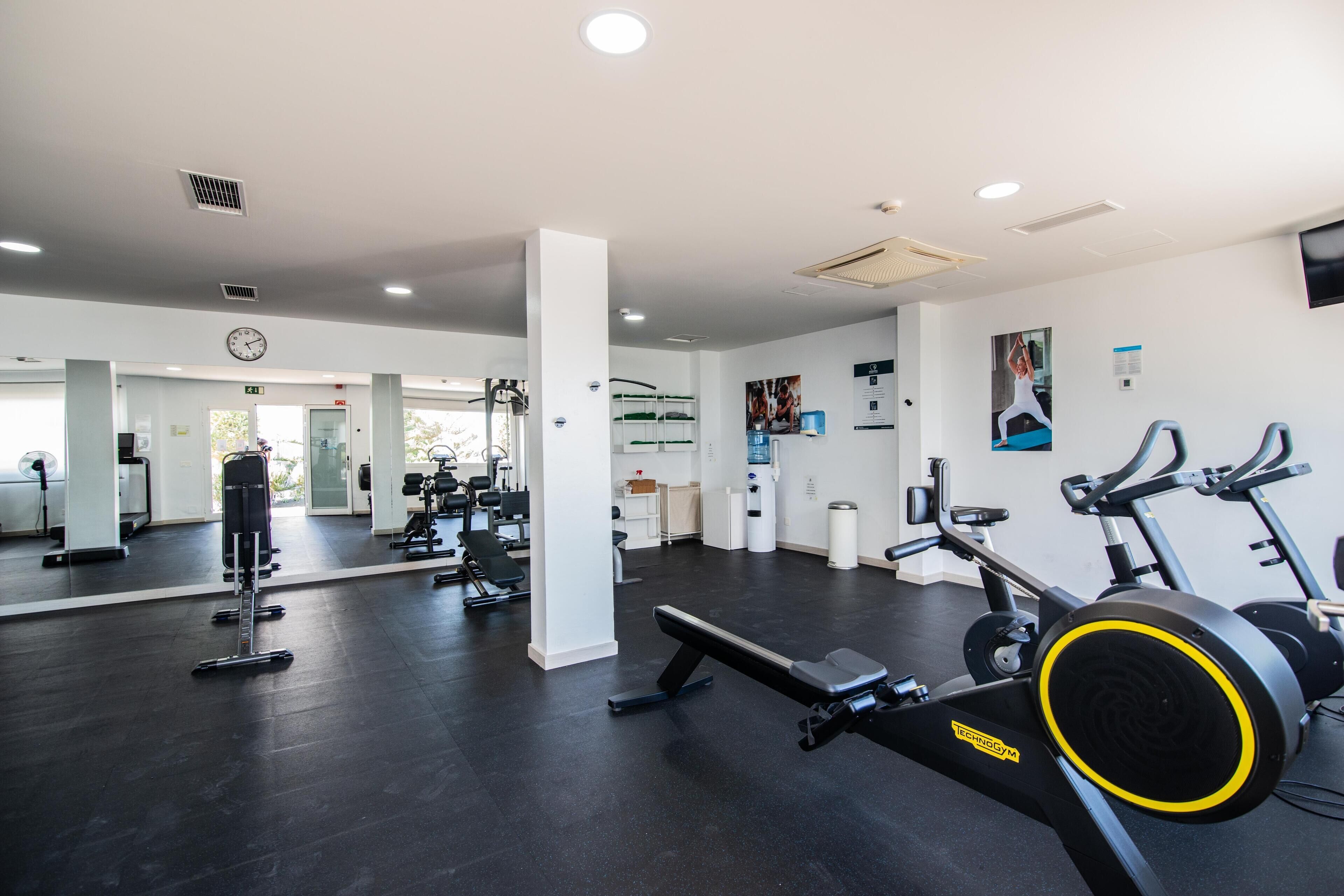 A gym with exercise equipment, a clock, and a mirror.