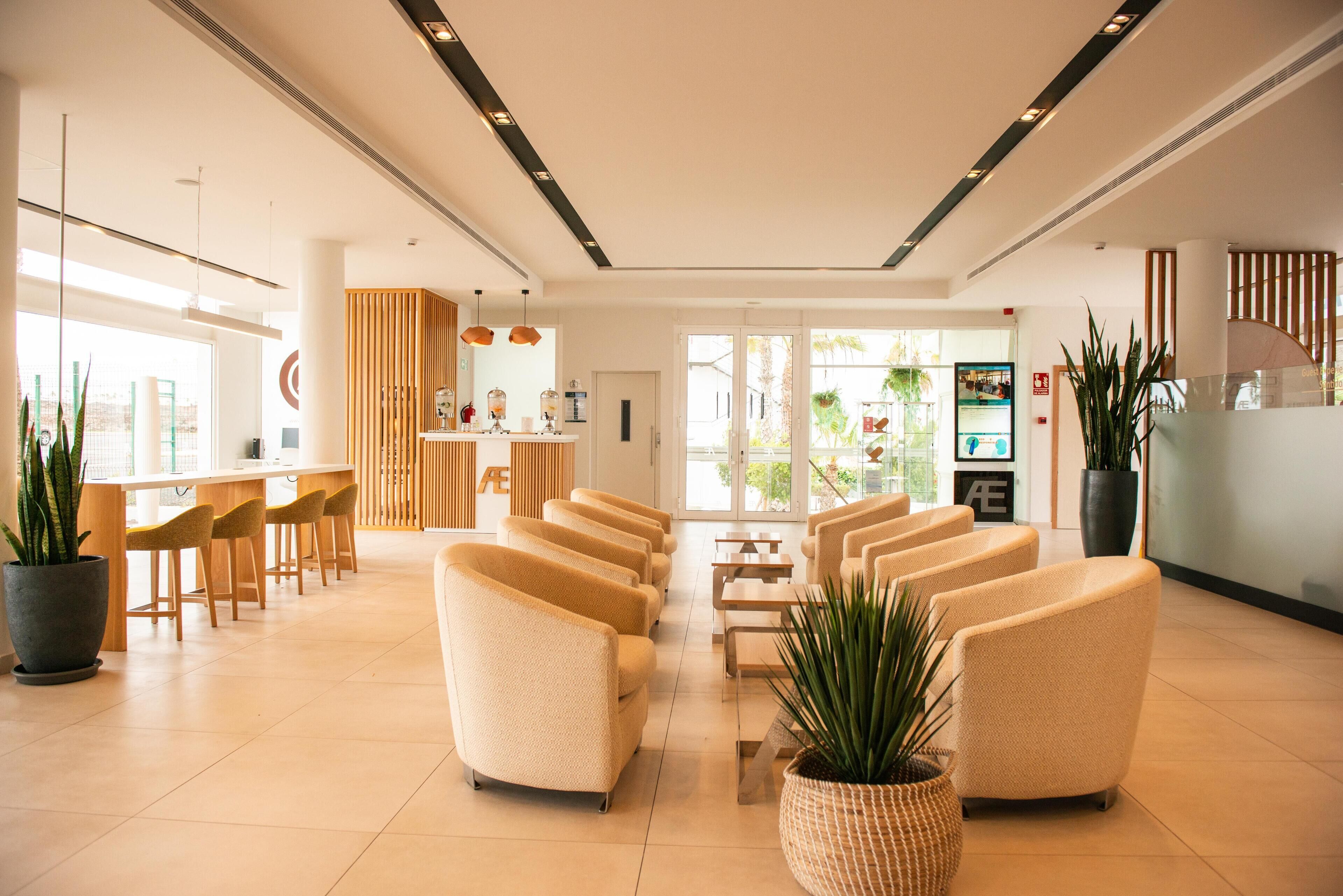 A modern lobby with a reception desk, seating area, and large windows.