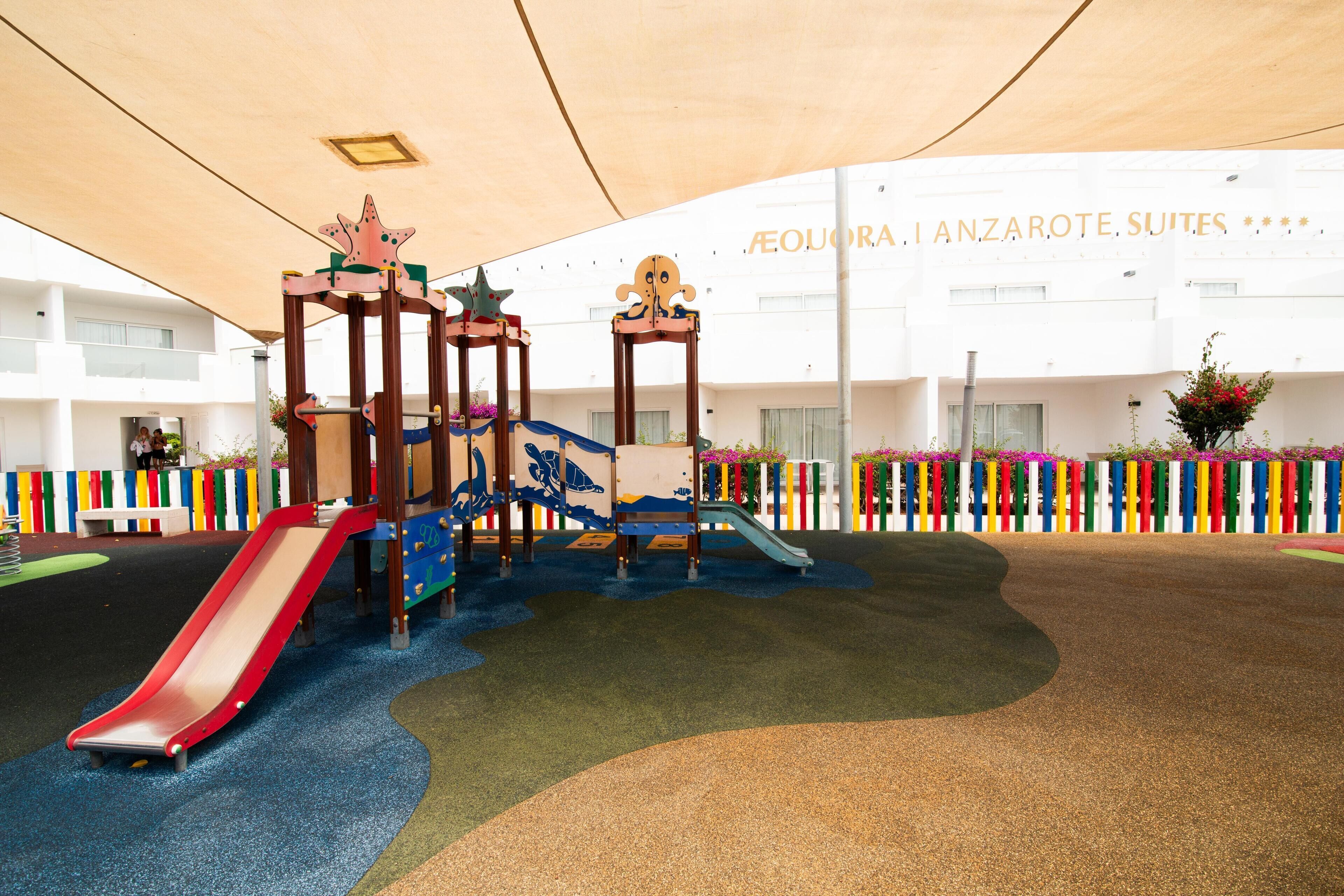 A children's play area with slides and climbing structures, surrounded by colorful vertical gardens.