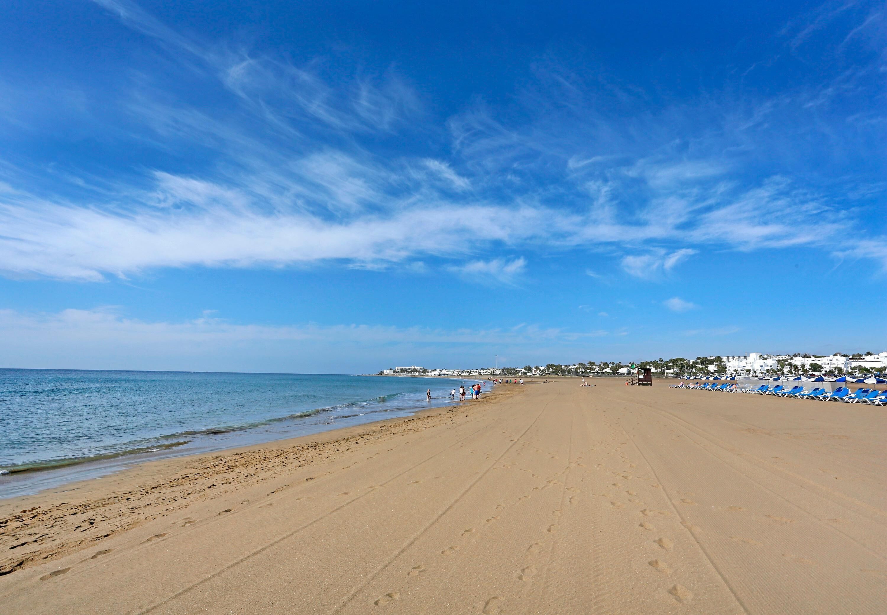 Perto da praia, areia branca, espreguiçadeiras, guarda-sóis 