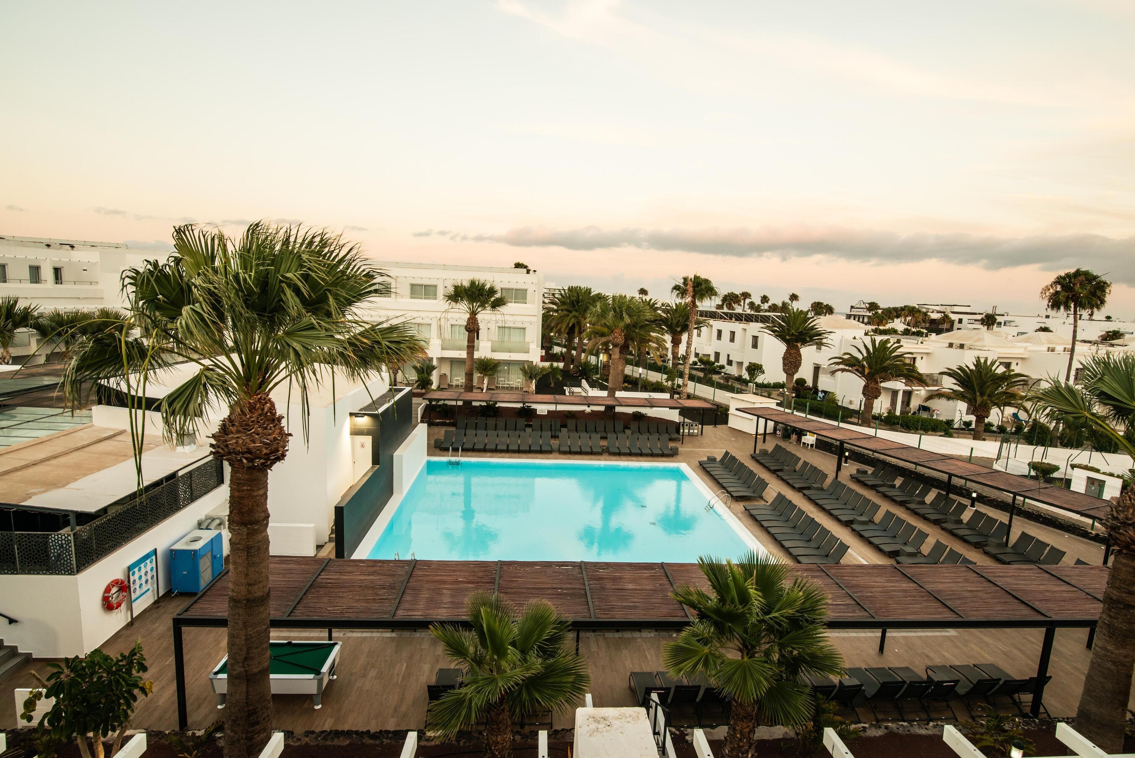 A rooftop pool area with multiple lounge chairs and a pool.