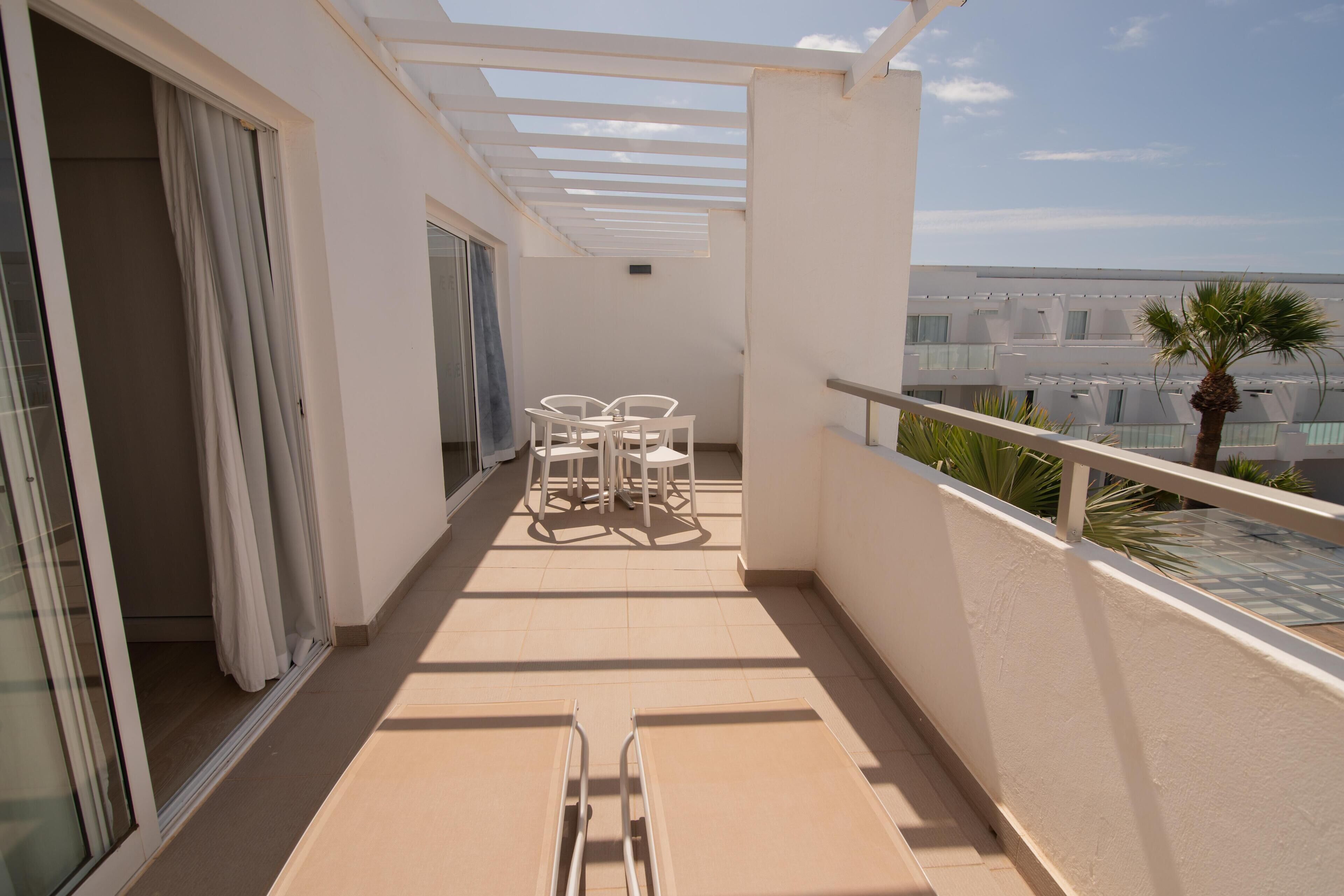 A balcony with a table and chairs, a sliding door, and a view of buildings.