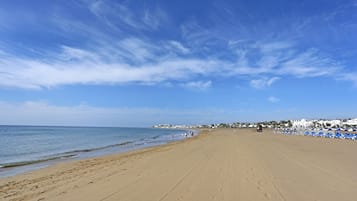 Perto da praia, areia branca, espreguiçadeiras, guarda-sóis 