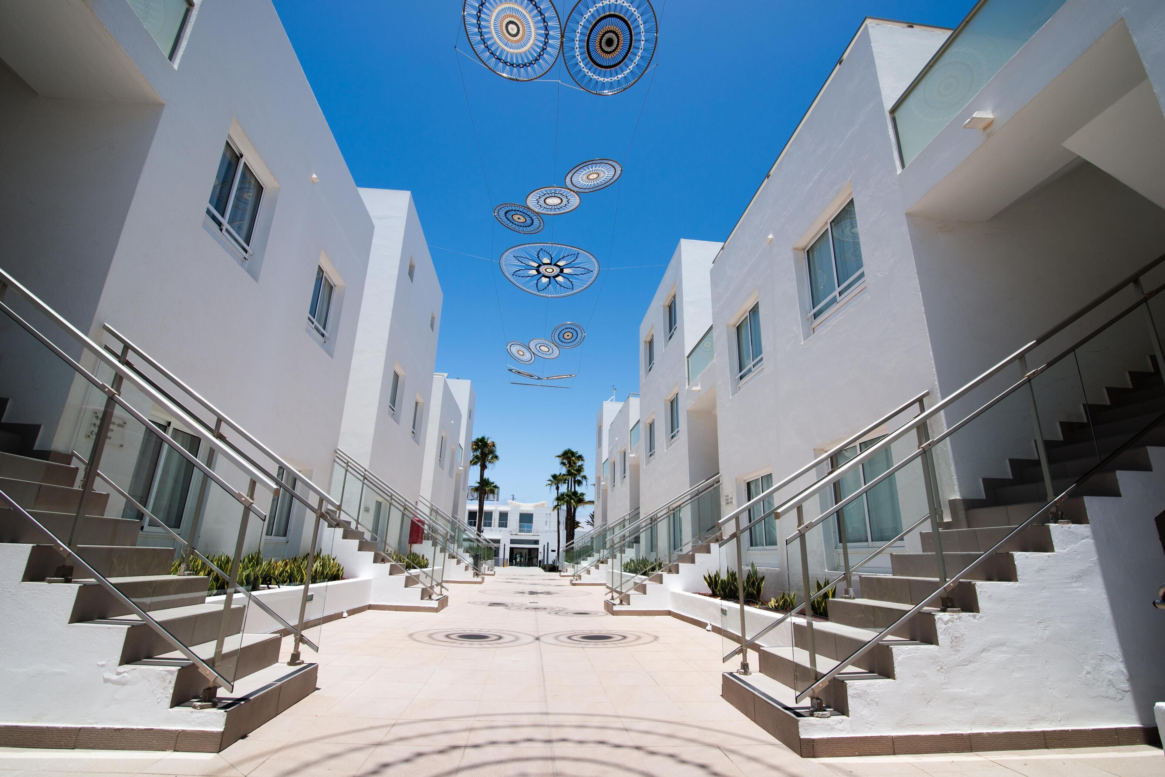 A modern building with a central staircase, glass railings, and a geometric ceiling design.