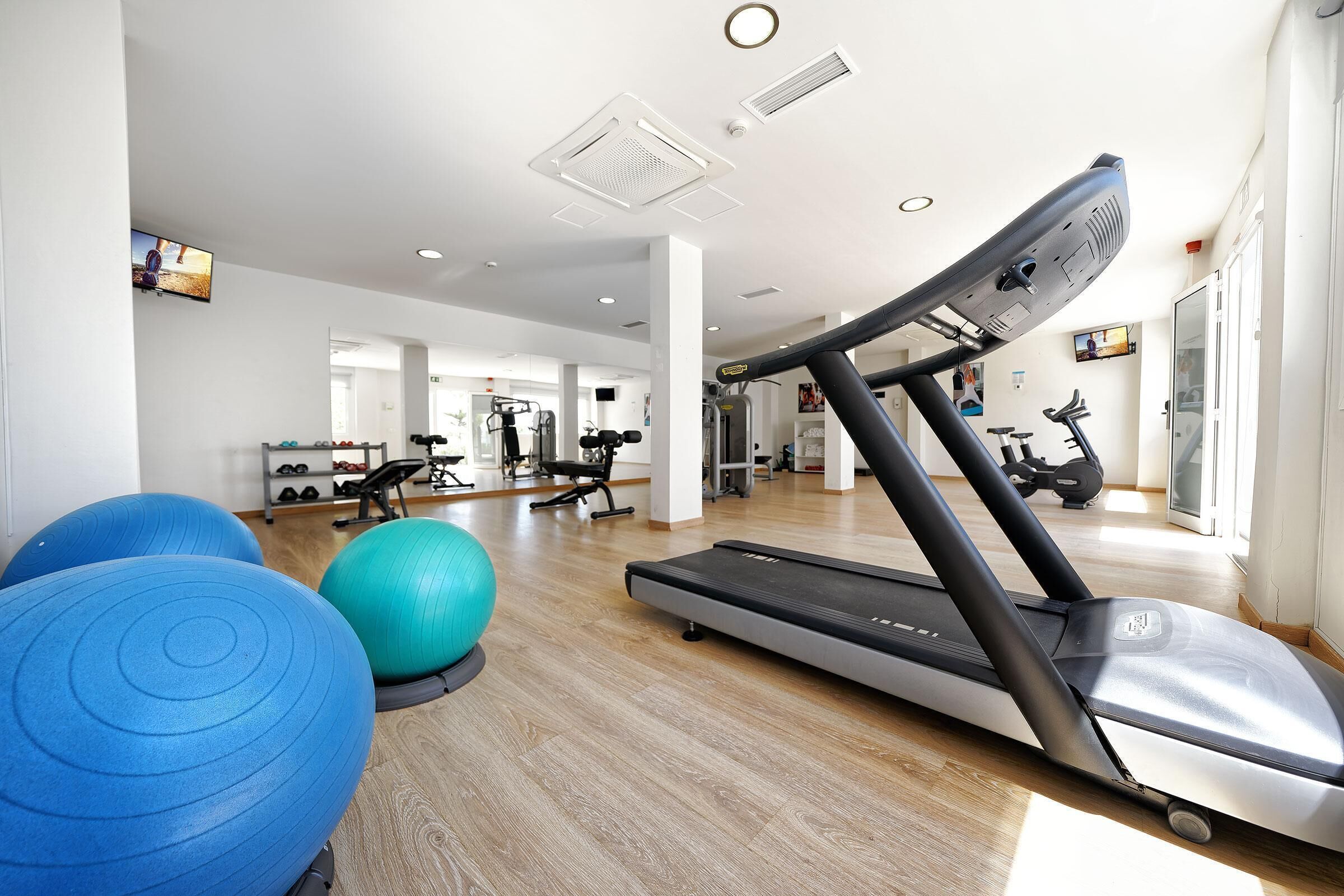 A gym with exercise equipment, including a treadmill, exercise balls, and weights.