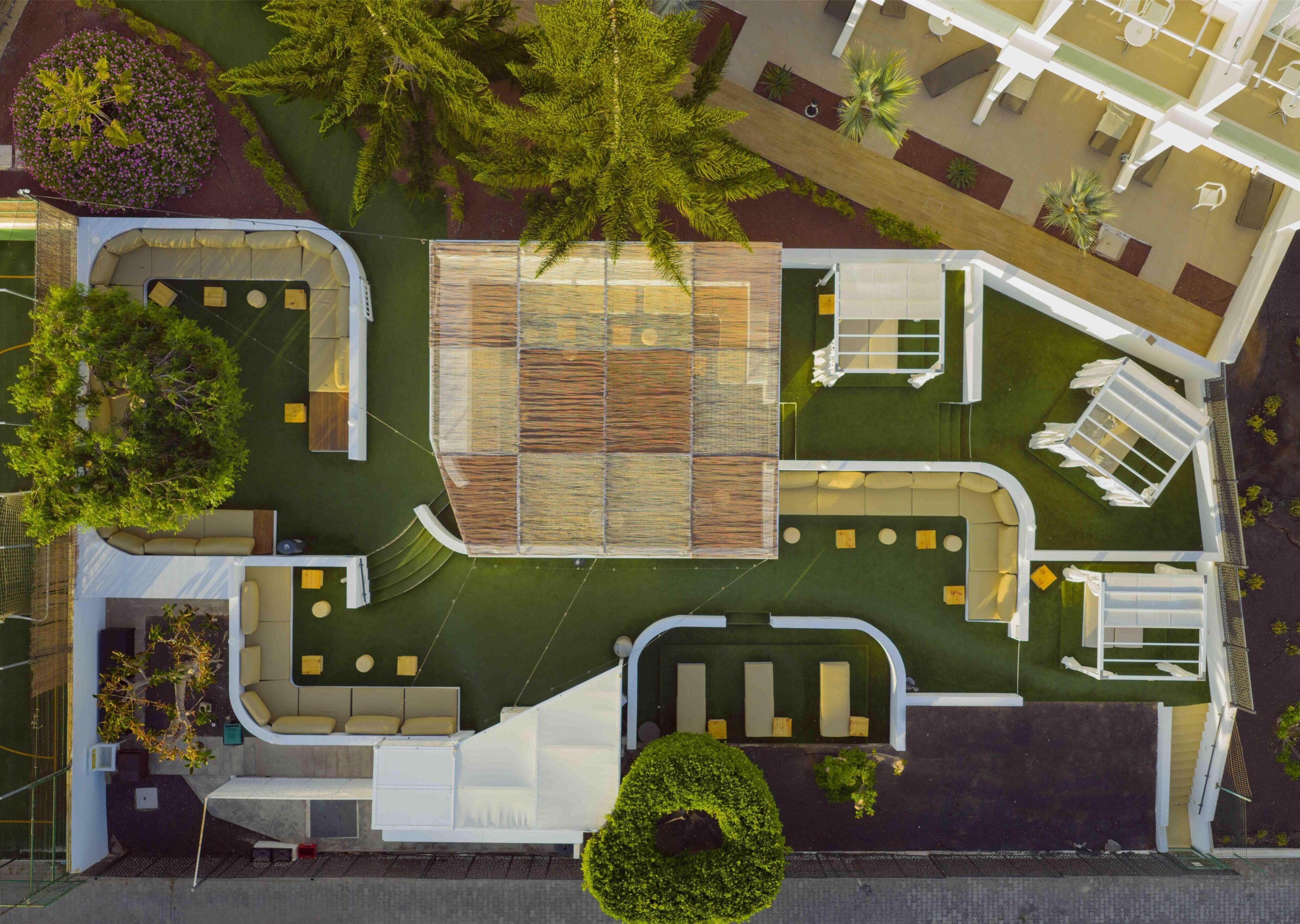 Vista aérea de un hotel con un patio central, zonas de estar al aire libre y vegetación circundante.