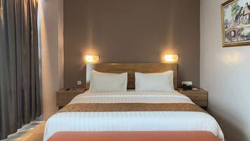 Habitación de hotel con una cama grande, dos mesitas de noche, un banco y un cuadro en la pared.