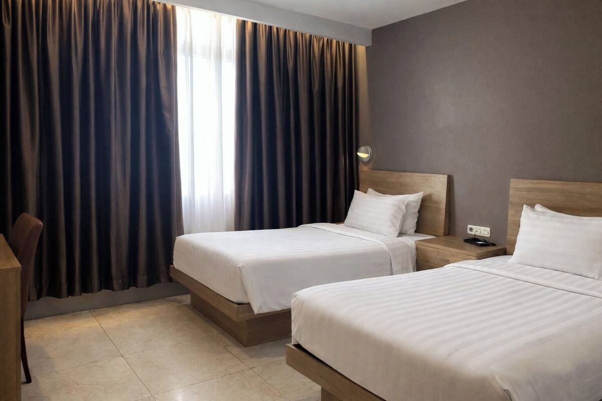A hotel room with two beds, a desk, and a chair.