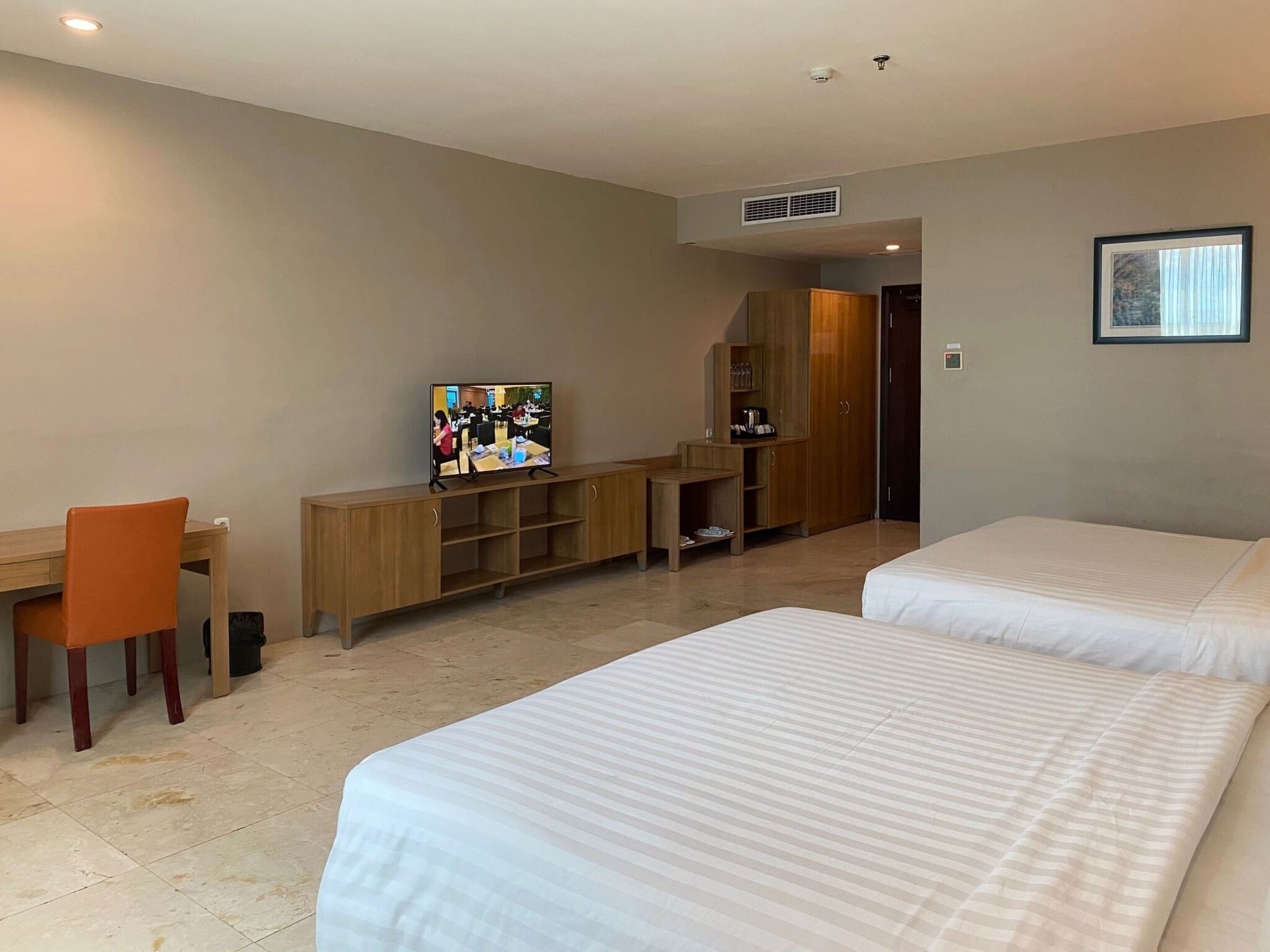 Une chambre d’hôtel avec deux lits, un bureau, une télévision et une armoire.