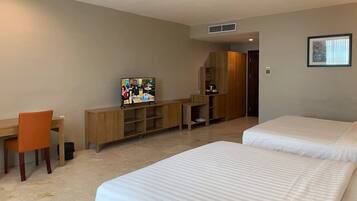 Une chambre d’hôtel avec deux lits, un bureau, une télévision et une armoire.
