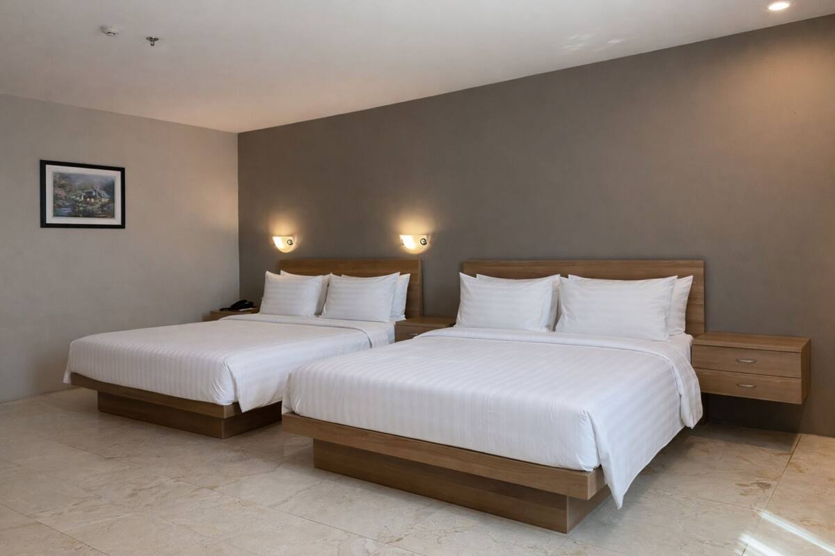 A hotel room with two beds, a nightstand, and a wall-mounted picture.