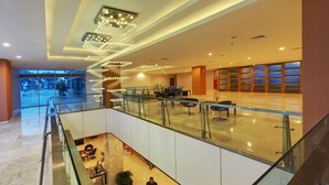 Un intérieur moderne avec une balustrade en verre, une personne debout et une vue sur l’extérieur.
