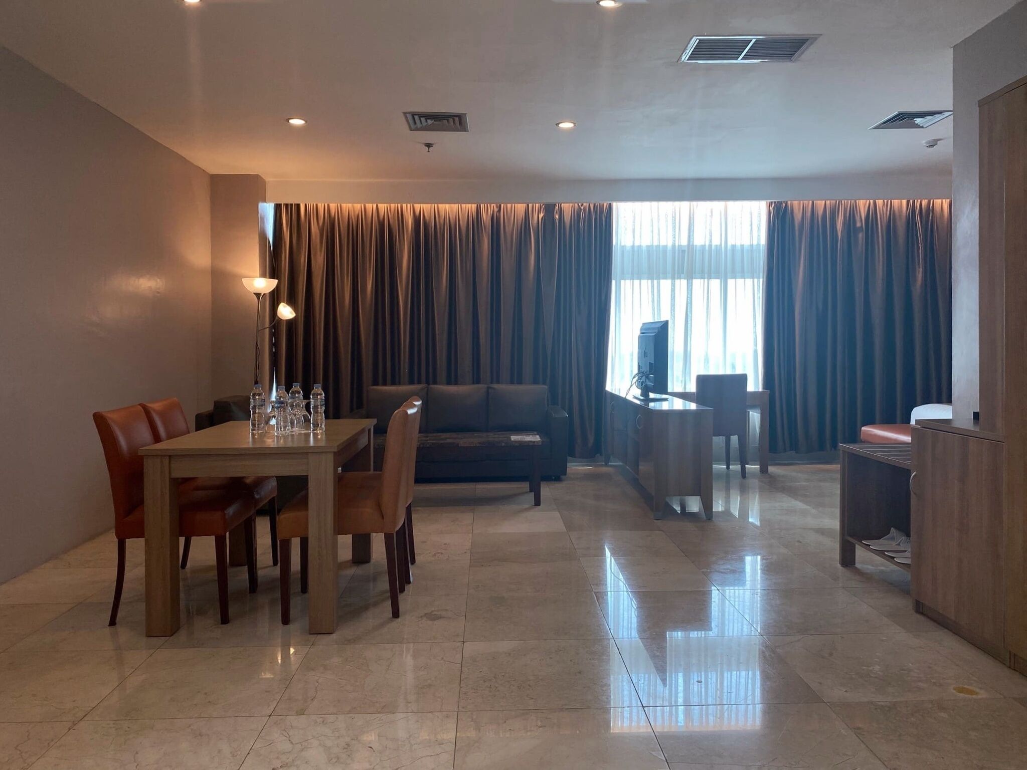 A spacious living area with a dining table, sofa, and TV stand.