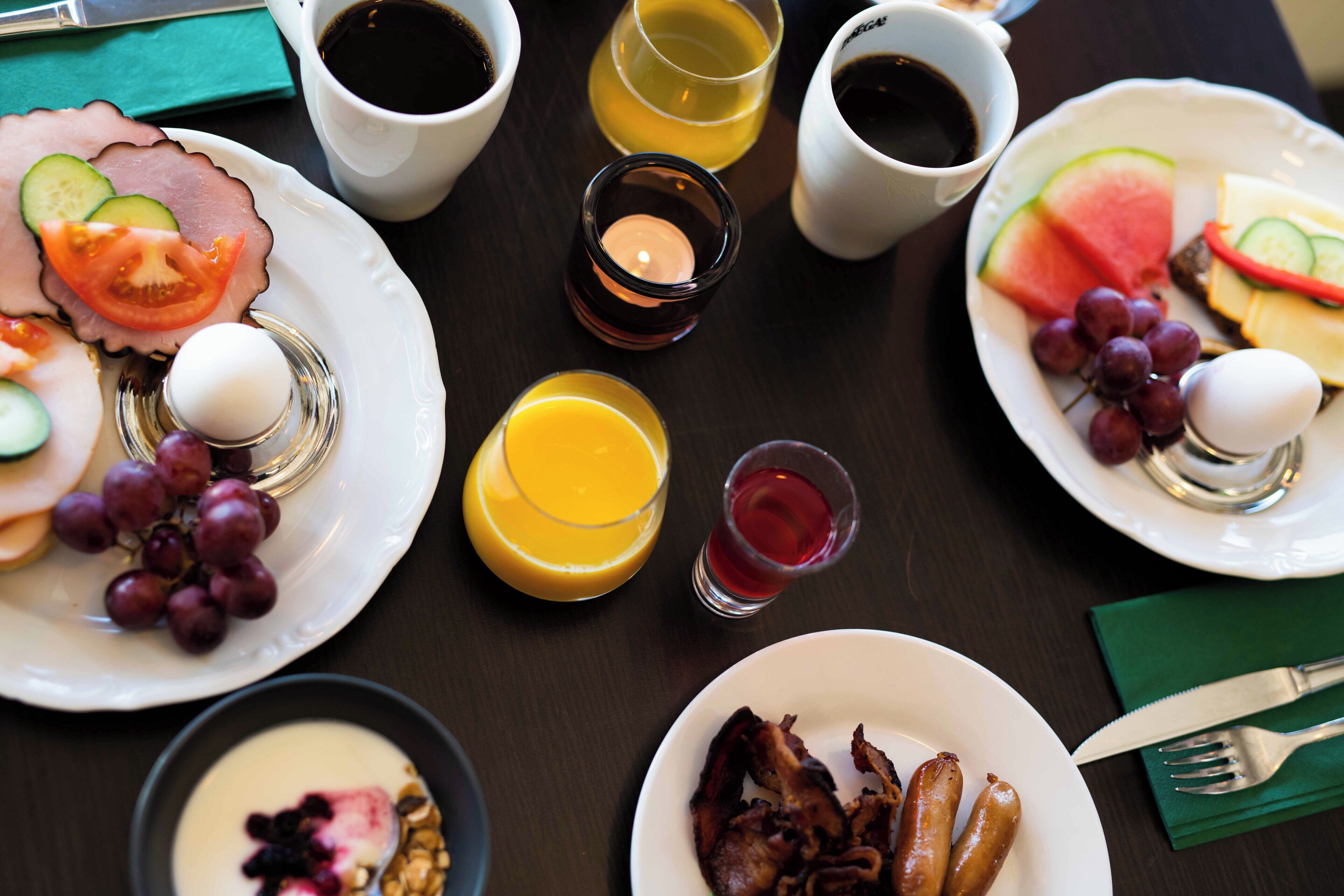 A breakfast setting with plates of food, cups of coffee, and a candle.