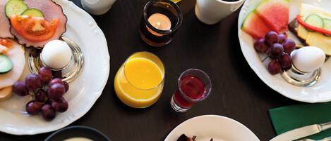 A breakfast setting with plates of food, cups of coffee, and a candle.