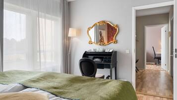 Une chambre d’hôtel avec un lit, un bureau avec une lampe, un miroir et une vue sur une autre chambre.