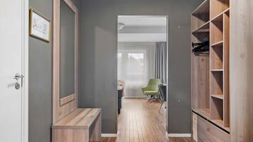 A hallway with a wooden bench, a green chair, and a wooden wardrobe with shelves.
