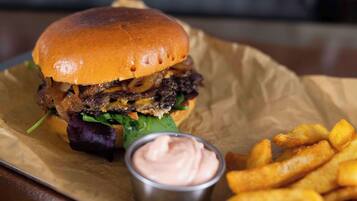 A burger with fries and a dipping sauce on a paper-lined tray.