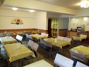 A hotel dining area with multiple tables and chairs, a reception desk, and a decorative wall piece. - Hua Tong Hotel (Hualien City)