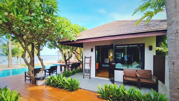 Una propiedad frente al mar con una terraza de madera, mobiliario exterior y una piscina.