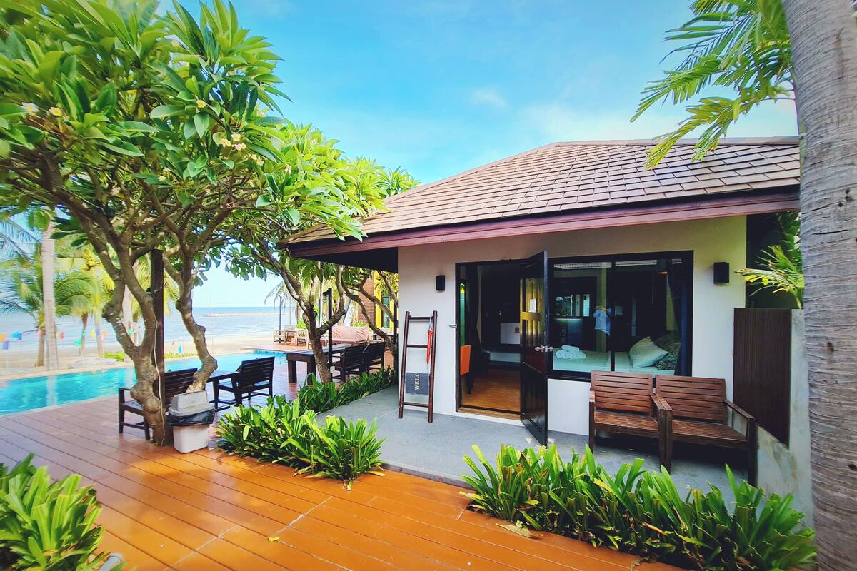 A beachfront property with a wooden deck, outdoor seating, and a pool.