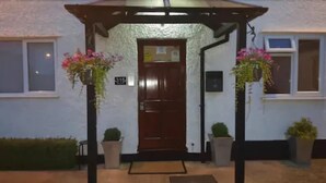 A building entrance with a wooden door, a sign above the door, and two flower baskets on either side. - The Balkan Lodge Oxford  (Oxford)