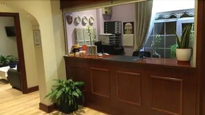 A reception area with a wooden counter, a potted plant, and a mirror reflecting the interior. - The Balkan Lodge Oxford  (Oxford)