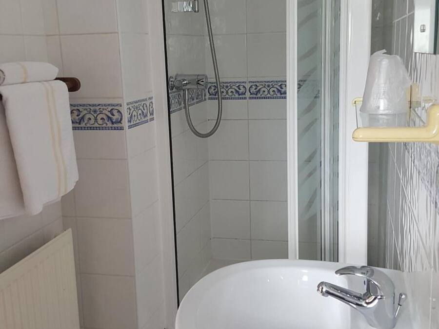 A bathroom with a white sink, a glass shower enclosure, and a towel rack.